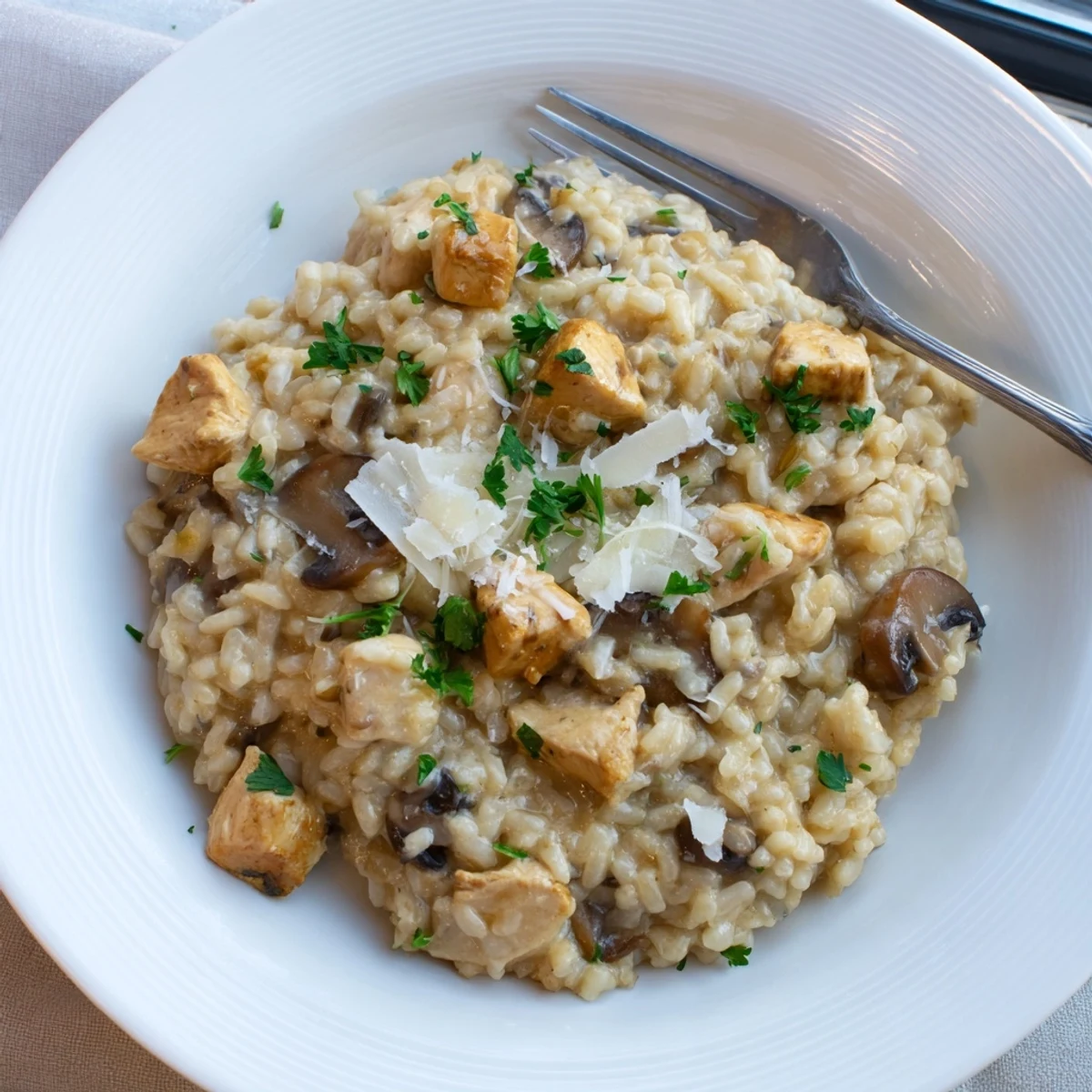 Steaming oven-baked chicken and mushroom risotto topped with extra Parmesan and vibrant green parsley
