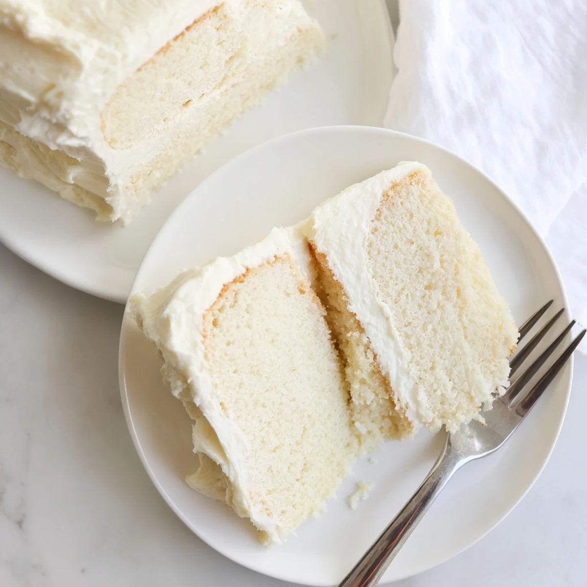 Golden slice of perfect vanilla cake revealing moist white crumb beneath creamy buttercream layers