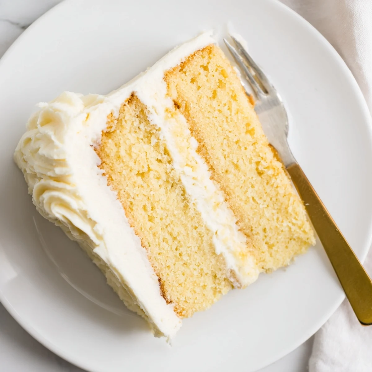 Two-layer perfect vanilla cake with tall slice showing tender texture and vanilla frosting