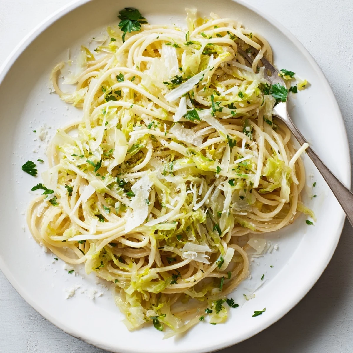 Close-up of spaghetti noodles coated in zesty lemon garlic sauce with wilted green cabbage