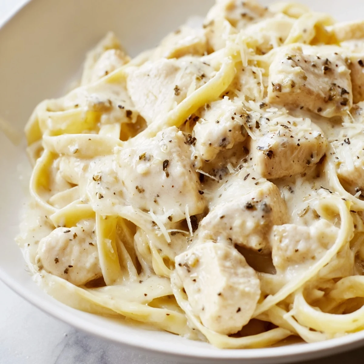 Creamy Instant Pot Chicken Alfredo with tender chicken pieces coated in rich parmesan garlic sauce over fettuccine