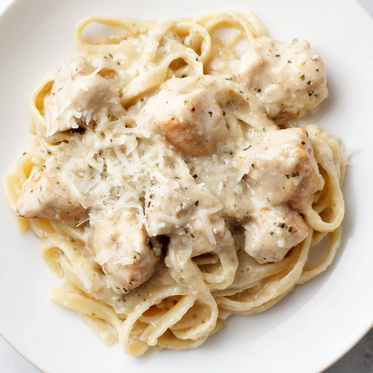 Steaming bowl of Italian-American Chicken Alfredo featuring perfectly cooked pasta and juicy chicken in a velvety cream sauce