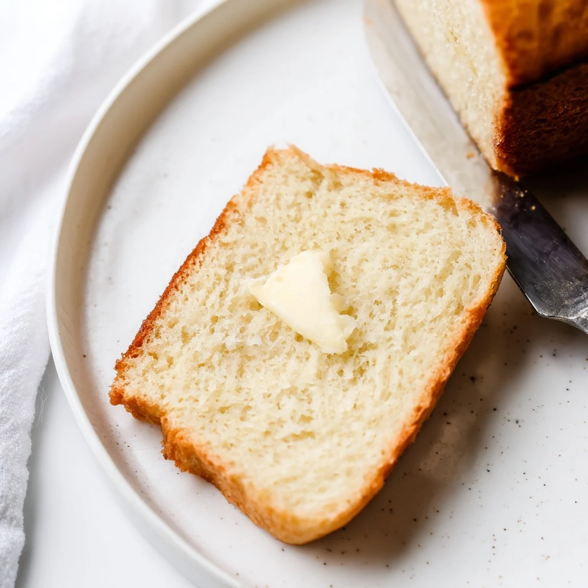 Golden zero carb yogurt bread loaf sliced on wooden board with butter melting