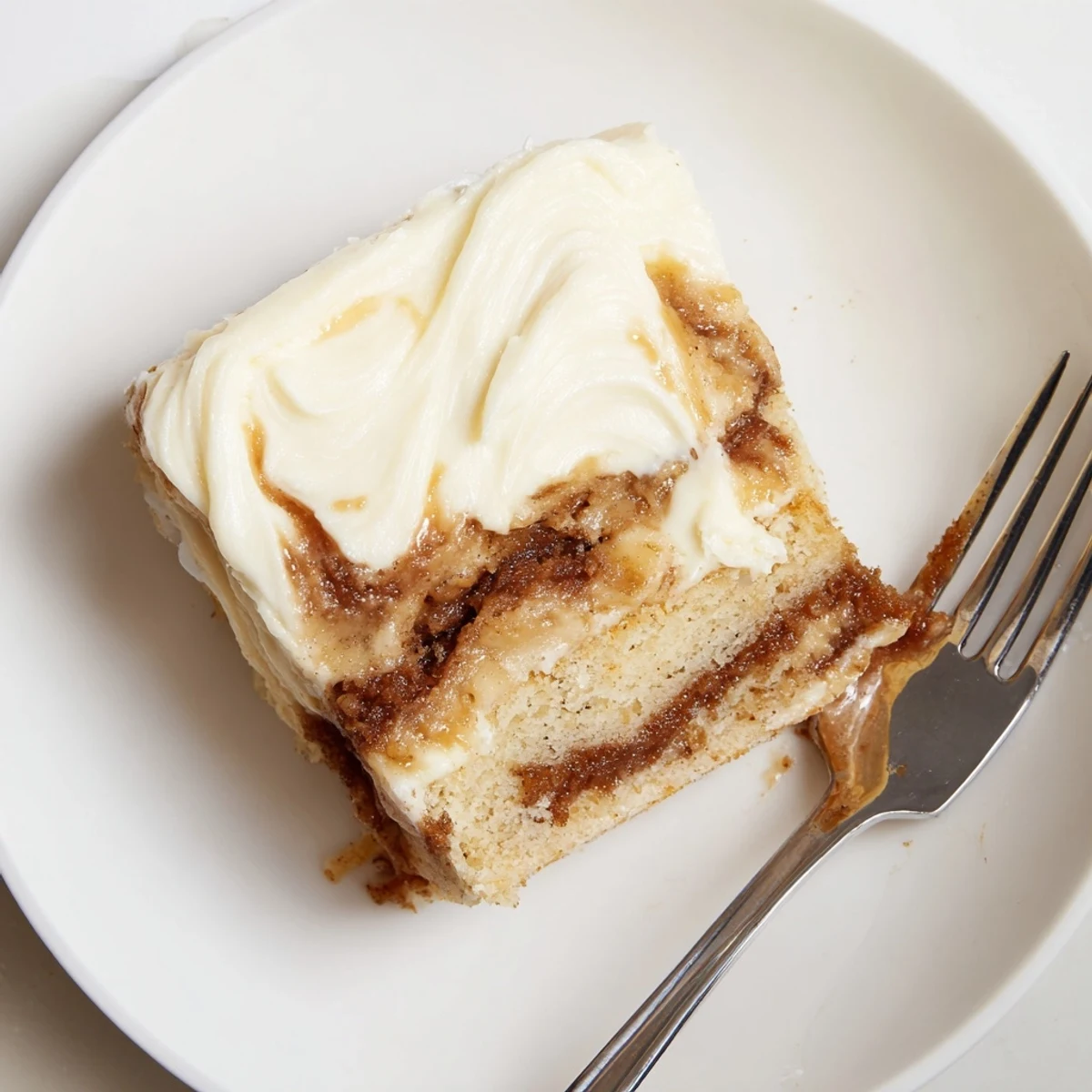 Warm Cinnamon Roll Poke Cake sliced for brunch, gooey swirls steaming