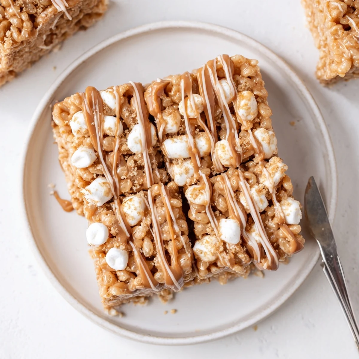 Biscoff Rice Krispie Treats: glossy caramel swirls, crispy cereal squares cooling on parchment