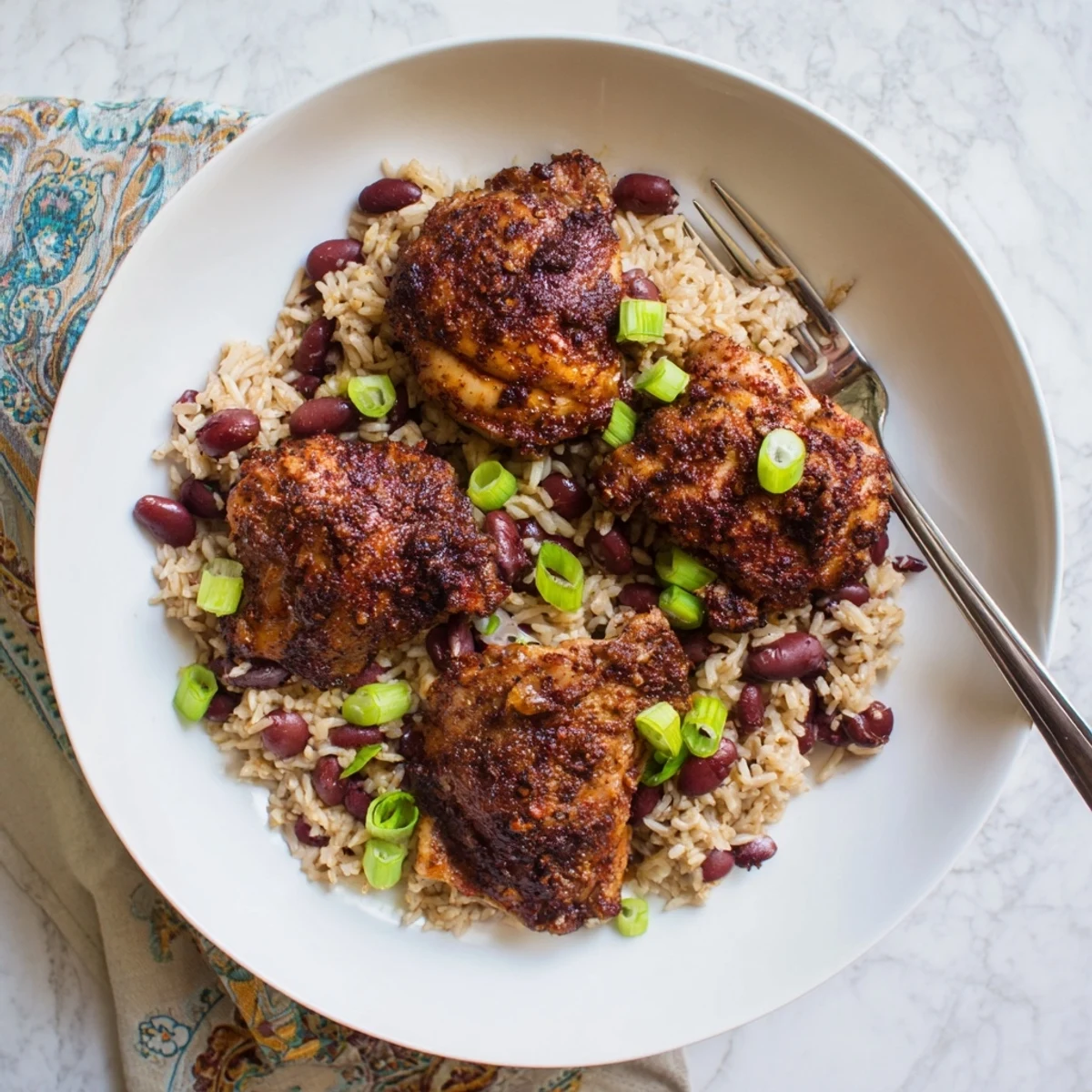 Close-up of tender jerk chicken with crispy skin atop steaming coconut rice with kidney beans