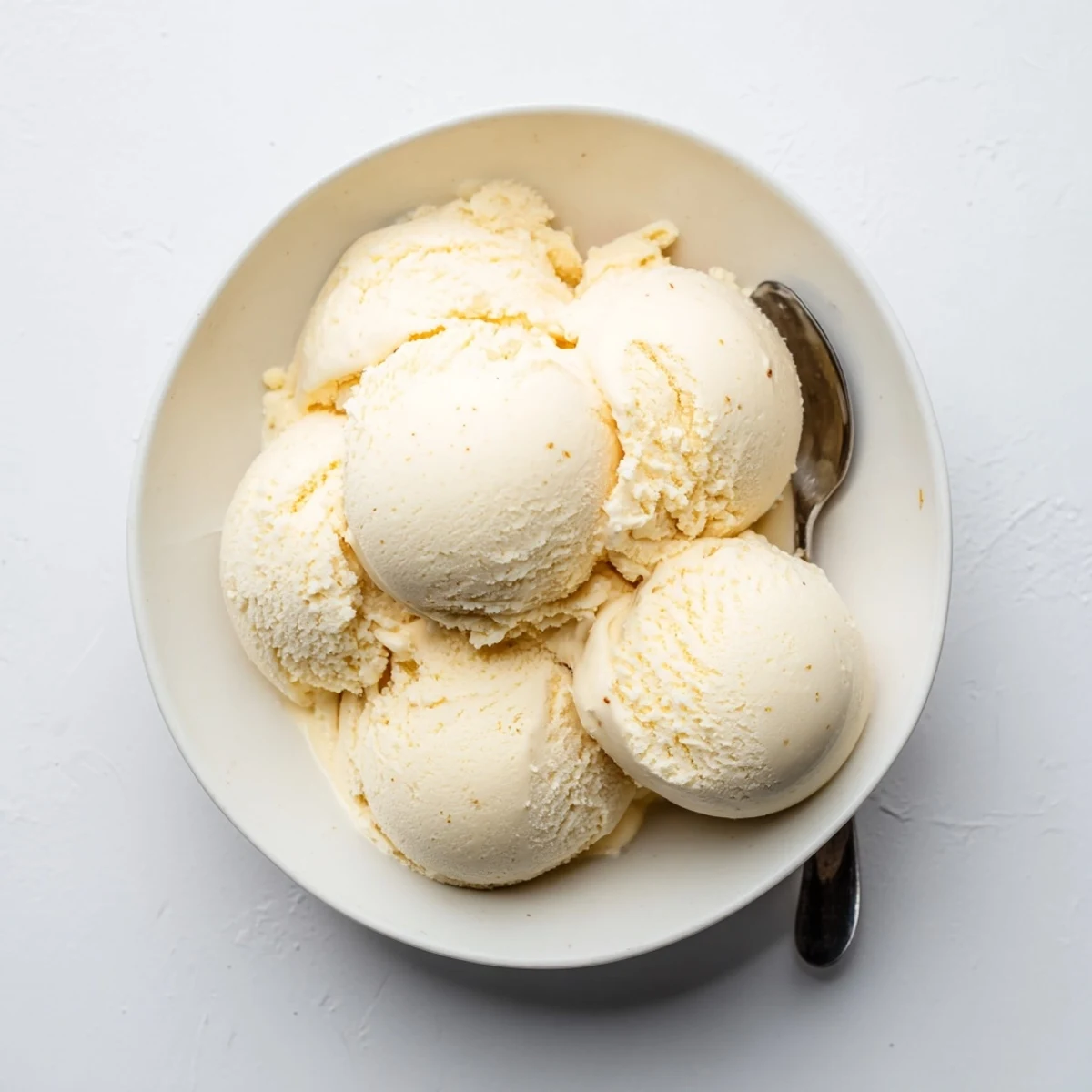Perfect scoop of velvety vanilla ice cream garnished with fresh mint leaf on white plate