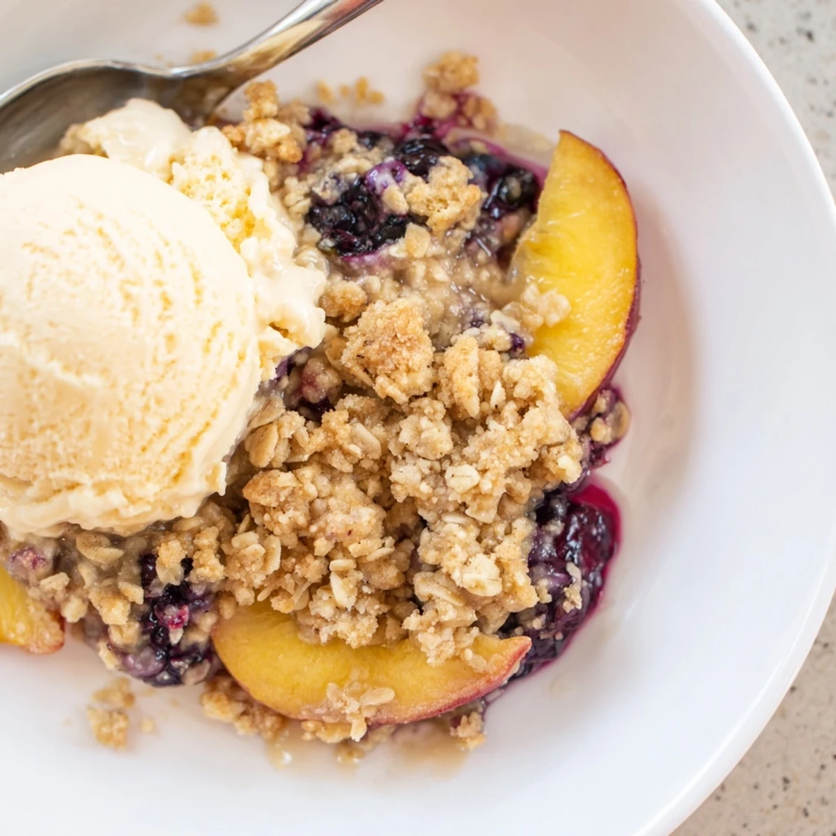 Blueberry Peach Crumble bubbling in a baking dish, golden top and steam rising