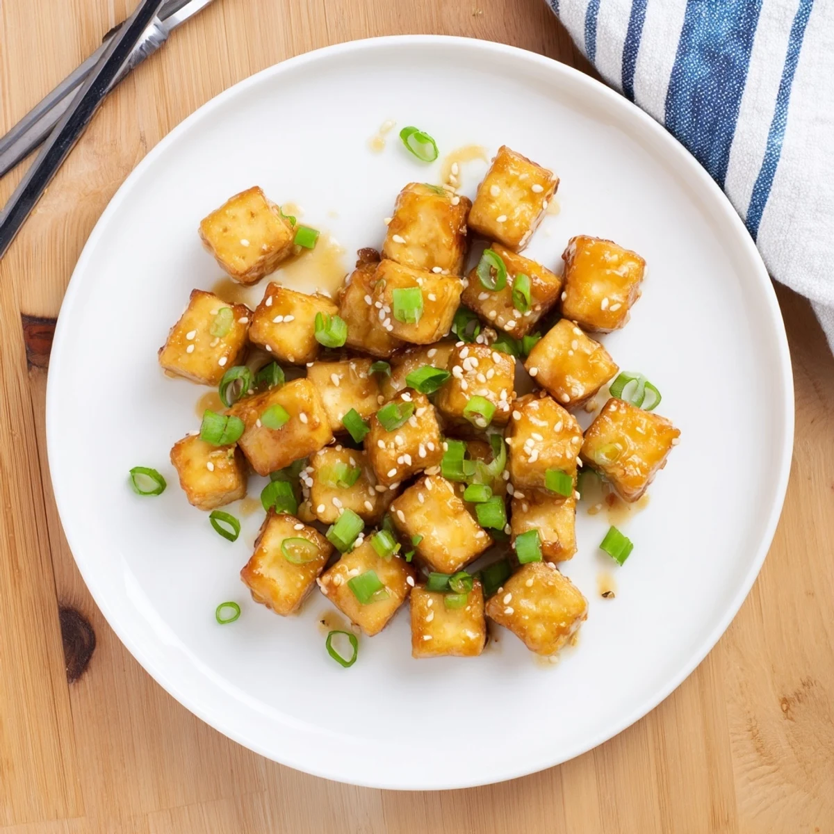 Crispy honey garlic tofu served hot with green onion garnish over steamed white rice