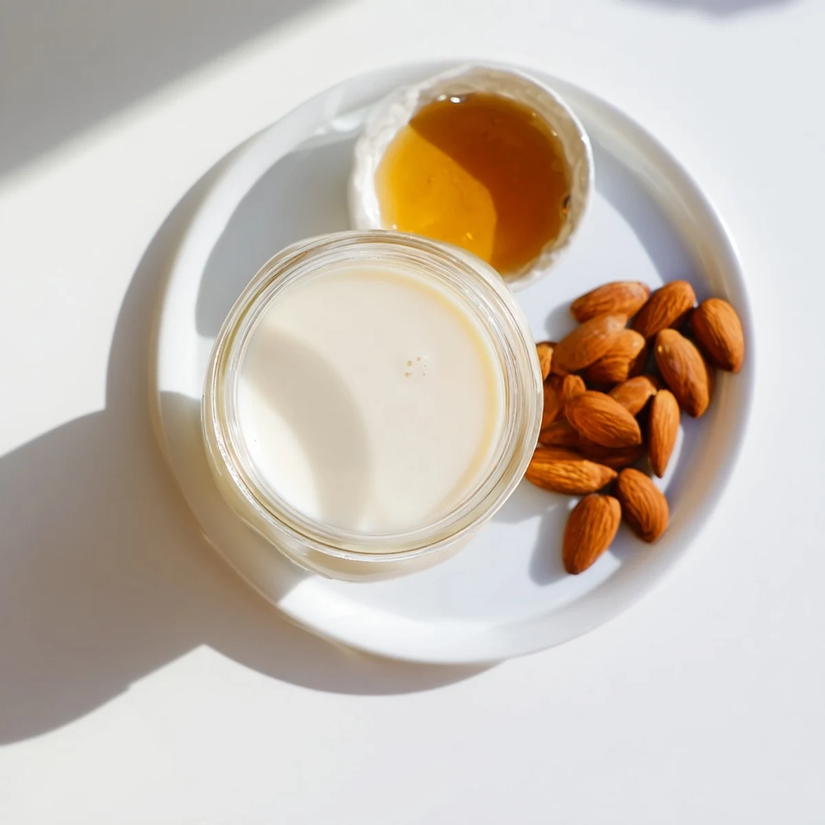 Fresh homemade almond milk poured into a clear glass jar with a creamy white texture
