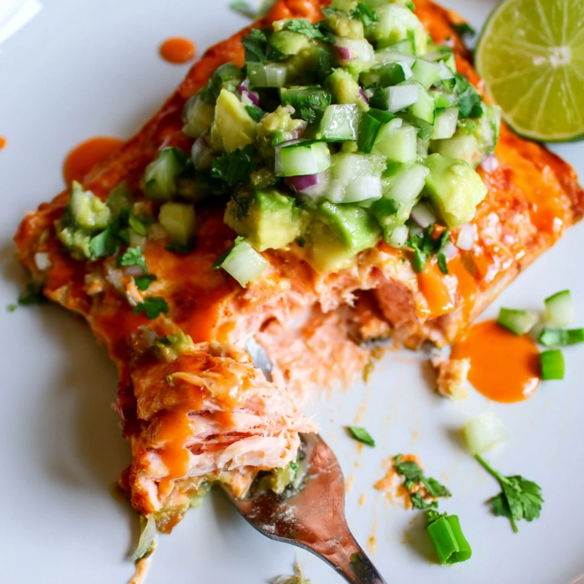 Golden bang bang salmon nestled beside creamy avocado cucumber salsa ready for weeknight dinner