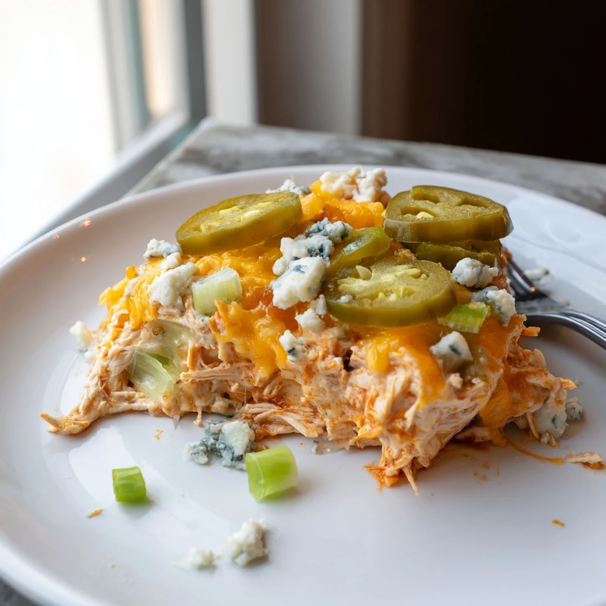 Creamy Jalapeno Buffalo Chicken Casserole topped with blue cheese crumbles and green onions