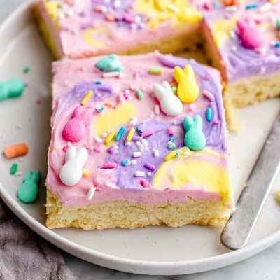 Thick buttery Easter sugar cookie bars sliced into squares topped with swirled frosting