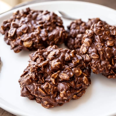 Glossy chocolate oatmeal no bake cookies studded with hearty oats and drizzled peanut butter