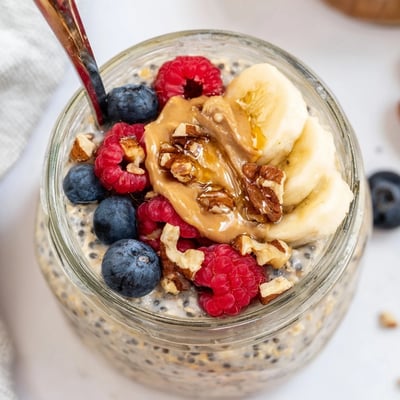 Thick protein overnight oats in a mason jar, layered with sliced banana and chopped nuts for a satisfying breakfast